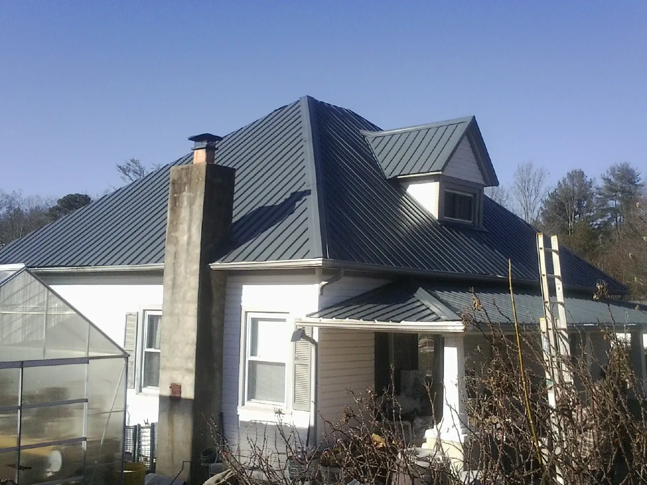 Dark blue standing seam metal roof on a white farmhouse with dormer — Slate & Tile Roof Repair by Roofing Brothers in Rapidan