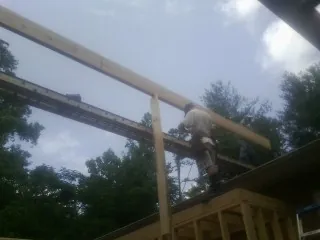 Carpenter setting a ridge beam over a new addition frame — Ice Dam Removal by Roofing Brothers in Rapidan