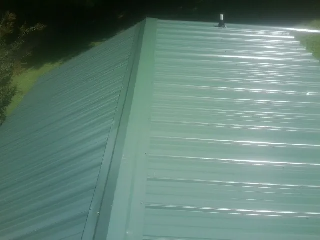 New green metal panels meeting at the ridge of a roof — Flat Roof Repair work by our crew in Rapidan