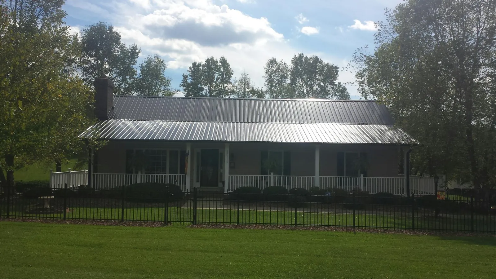 Gray metal roof on a brick ranch with a full width front porch — Gutter Guard Installation work by our crew in Rapidan