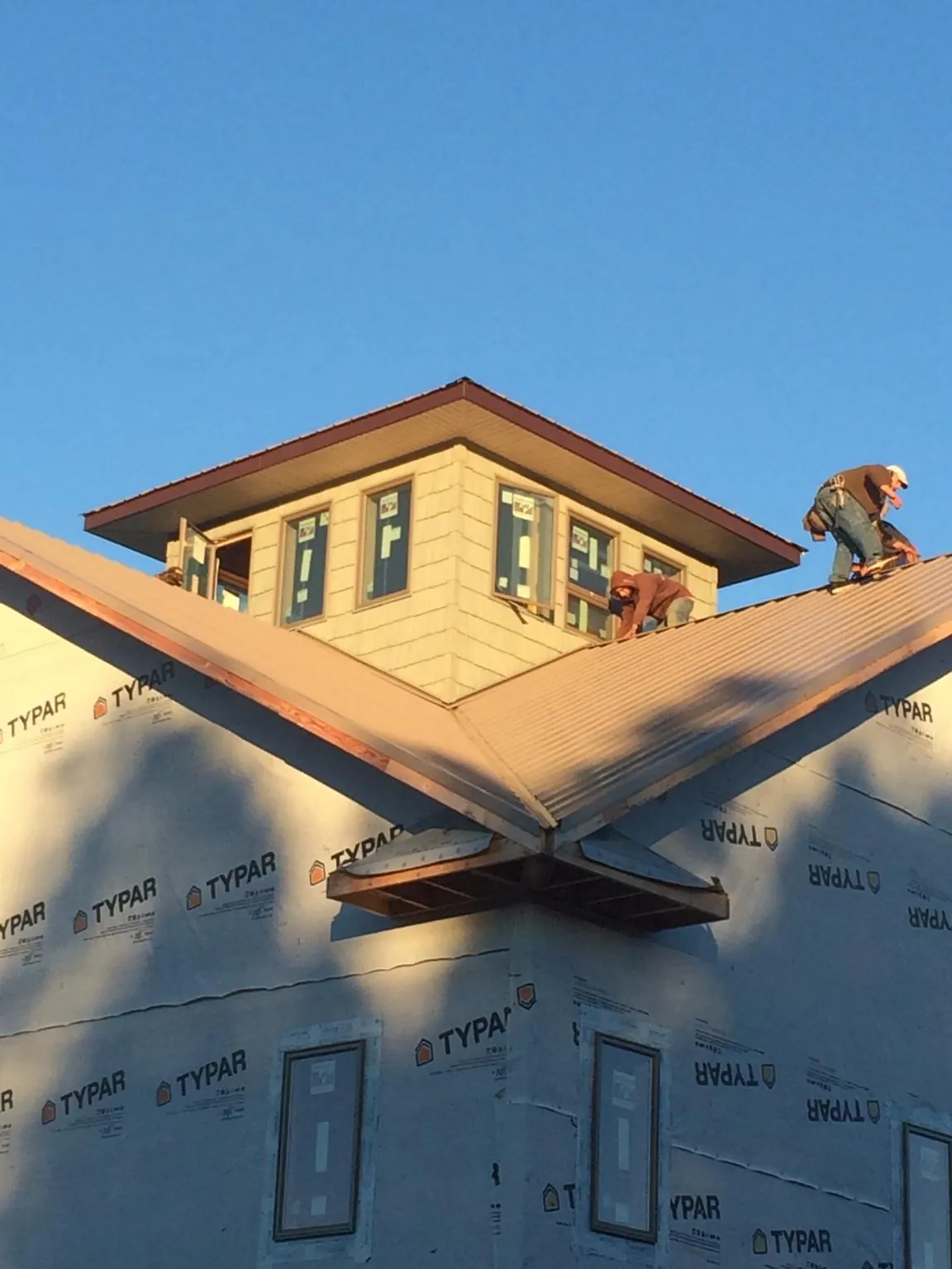 Roofers working around a rooftop cupola on a new metal roof at sunset — Roof Waterproofing in Rapidan by Roofing Brothers